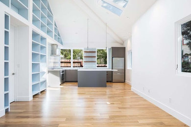 Modern l-shaped kitchen in San Francisco with an undermount sink, flat-panel cabinets, grey cabinets, white splashback, glass tile splashback, stainless steel appliances, medium hardwood floors and with island.