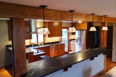 Example of a mid-sized classic medium tone wood floor kitchen design in Boston with an undermount sink, raised-panel cabinets, medium tone wood cabinets, granite countertops, white backsplash and stainless steel appliances