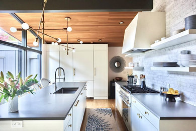 Foto de cocina clásica renovada con electrodomésticos con paneles, suelo de madera clara, una isla y madera