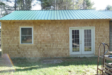 Large elegant brown one-story wood exterior home photo in Portland Maine with a metal roof