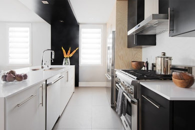 Kitchen - modern single-wall ceramic tile kitchen idea in Montreal with flat-panel cabinets, black cabinets, quartzite countertops, ceramic backsplash, stainless steel appliances and an island