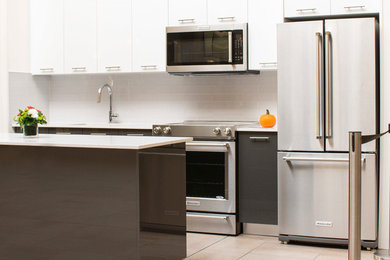 Mid-sized minimalist single-wall eat-in kitchen photo in Toronto with an undermount sink, flat-panel cabinets, white cabinets, white backsplash, ceramic backsplash, stainless steel appliances and an island