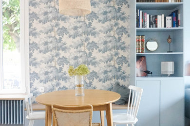 Idée de décoration pour une salle à manger ouverte sur le salon design de taille moyenne avec un mur bleu, un sol en bois brun et du papier peint.
