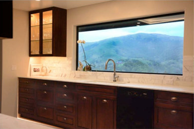Kitchen - traditional kitchen idea in San Francisco with an undermount sink, recessed-panel cabinets, dark wood cabinets, white backsplash, marble backsplash, black appliances and white countertops
