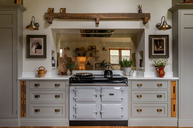 This is an example of a classic grey and white kitchen/diner in Other with a belfast sink, shaker cabinets, grey cabinets, quartz worktops, white splashback, medium hardwood flooring, no island and white worktops.