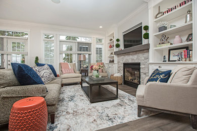 Photo of a mid-sized contemporary open concept living room in Other with white walls, medium hardwood floors, a standard fireplace, a stone fireplace surround, a wall-mounted tv and grey floor.