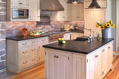 Inspiration for a large farmhouse u-shaped light wood floor enclosed kitchen remodel in Philadelphia with a farmhouse sink, beaded inset cabinets, white cabinets, soapstone countertops, blue backsplash, ceramic backsplash, paneled appliances and an island
