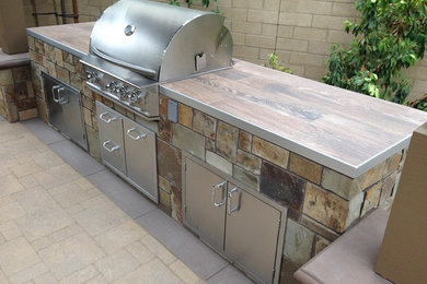 Patio kitchen - mid-sized contemporary backyard stone patio kitchen idea in Orange County with a roof extension