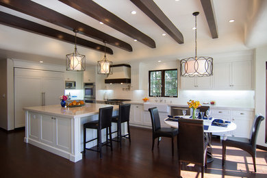 This is an example of a traditional l-shaped eat-in kitchen in Los Angeles with a farmhouse sink, recessed-panel cabinets, white cabinets, white splashback and panelled appliances.