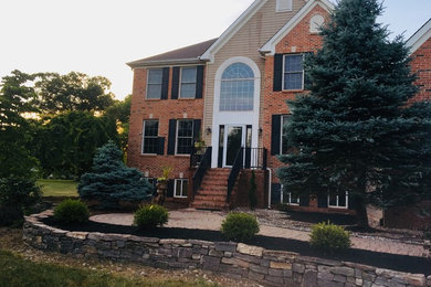 Photo of a large traditional shade front yard concrete paver retaining wall landscape in New York.