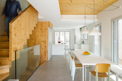 Imagen de comedor nórdico de tamaño medio abierto con paredes blancas, suelo de baldosas de porcelana, suelo gris, madera y madera