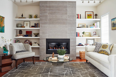 Design ideas for a small modern enclosed family room in Richmond with a library, white walls, medium hardwood floors, a standard fireplace, a tile fireplace surround, no tv and brown floor.