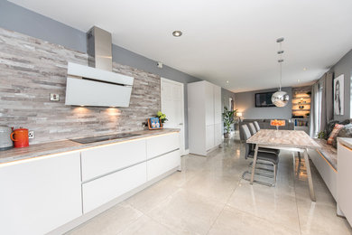 Photo of a contemporary eat-in kitchen in Other with flat-panel cabinets, white cabinets, beige splashback, white appliances, porcelain floors and beige floor.
