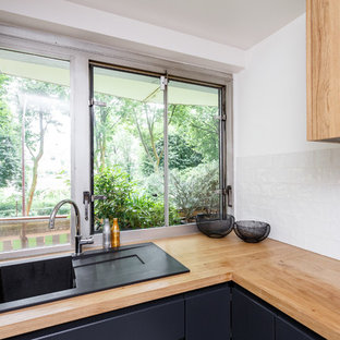 Удачное сочетание для дизайна помещения: маленькая отдельная, угловая кухня в скандинавском стиле с накладной раковиной, плоскими фасадами, черными фасадами, столешницей из дерева, белым фартуком, фартуком из керамической плитки, техникой из нержавеющей стали, полом из терраццо, разноцветным полом и коричневой столешницей без острова - самое интересное для вас