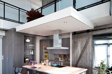 Mid-sized urban l-shaped medium tone wood floor eat-in kitchen photo in Toronto with a drop-in sink, shaker cabinets, brown cabinets, marble countertops, white backsplash, stainless steel appliances and an island