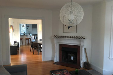 This is an example of a mid-sized transitional enclosed living room in Boston with white walls, light hardwood floors, a standard fireplace, a plaster fireplace surround, no tv and beige floor.