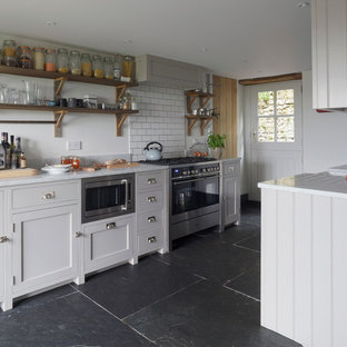 Пример оригинального дизайна интерьера: маленькая кухня в стиле кантри с фасадами в стиле шейкер, серыми фасадами, мраморной столешницей, белым фартуком, фартуком из плитки кабанчик, техникой из нержавеющей стали и черным полом без острова