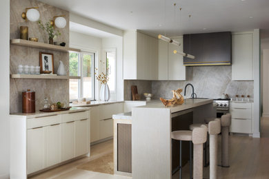 Inspiration for a large coastal u-shaped light wood floor and beige floor kitchen remodel in Providence with flat-panel cabinets, white cabinets, quartzite countertops, marble backsplash, an island, gray backsplash, stainless steel appliances and gray countertops