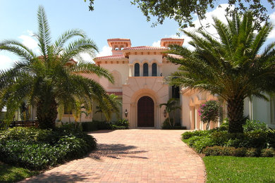 Inspiration for a huge mediterranean red two-story stucco exterior home remodel in Miami with a hip roof