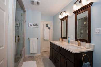Example of a mid-sized transitional master gray tile and porcelain tile porcelain tile and beige floor alcove shower design in Other with shaker cabinets, dark wood cabinets, a two-piece toilet, blue walls, an undermount sink, quartz countertops and a hinged shower door