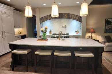 Large minimalist l-shaped ceramic tile and brown floor open concept kitchen photo in Other with a single-bowl sink, shaker cabinets, white cabinets, quartz countertops, white backsplash, quartz backsplash, stainless steel appliances, an island and white countertops