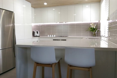 Design ideas for a large modern u-shaped open plan kitchen in Gold Coast - Tweed with a double-bowl sink, white cabinets, quartz benchtops, brown splashback, ceramic splashback, stainless steel appliances, porcelain floors and a peninsula.