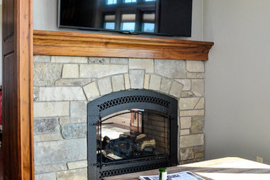 Photo of a transitional study room in Other with grey walls, dark hardwood floors, a standard fireplace, a stone fireplace surround and a freestanding desk.