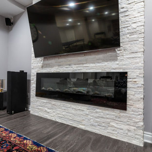 シカゴの大きいトランジショナルスタイルのおしゃれな地下室 (半地下 (ドアあり)、グレーの壁、クッションフロア、横長型暖炉、石材の暖炉まわり、グレーの床) の写真