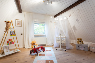 Mittelgroßes, Neutrales Modernes Babyzimmer mit weißer Wandfarbe, braunem Boden, Holzdielendecke und Holzdielenwänden in Köln