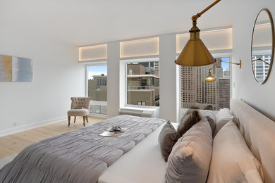 Modelo de dormitorio principal actual grande con paredes blancas, suelo de madera clara y suelo beige