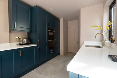 Inspiration for a small modern l-shaped kitchen/diner in Other with a submerged sink, shaker cabinets, blue cabinets, quartz worktops, white splashback, stone slab splashback, black appliances, porcelain flooring, a breakfast bar, beige floors, white worktops and feature lighting.