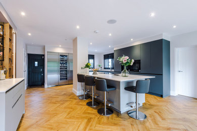 Photo of a large modern kitchen in Manchester with flat-panel cabinets, grey cabinets, quartz worktops, glass sheet splashback and stainless steel appliances.