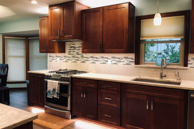 Photo of a large transitional galley eat-in kitchen in Kansas City with a double-bowl sink, shaker cabinets, medium wood cabinets, quartzite benchtops, multi-coloured splashback, ceramic splashback, stainless steel appliances, laminate floors, no island, brown floor and grey benchtop.