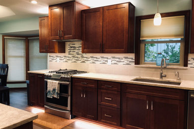 Inspiration for a large transitional galley laminate floor and brown floor eat-in kitchen remodel in Tampa with a double-bowl sink, shaker cabinets, medium tone wood cabinets, quartzite countertops, multicolored backsplash, ceramic backsplash, stainless steel appliances, no island and gray countertops