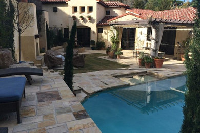 Photo of a large mediterranean backyard patio in Los Angeles with a fire feature, natural stone pavers and a pergola.