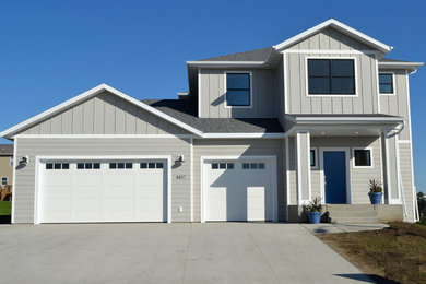 Photo of a mid-sized transitional two-storey grey house exterior in Other with vinyl siding, a hip roof and a shingle roof.