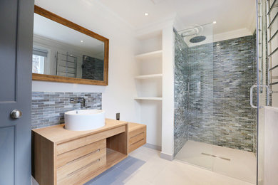 Contemporary 3/4 bathroom in London with flat-panel cabinets, light wood cabinets, an alcove shower, matchstick tile, white walls, a vessel sink, wood benchtops, gray tile, a hinged shower door and beige benchtops.