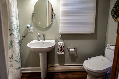 Example of a small transitional kids' green tile vinyl floor, brown floor and single-sink bathroom design in Cleveland with a two-piece toilet, green walls and a pedestal sink