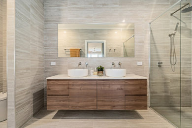 This is an example of a mid-sized contemporary bathroom in Sydney with flat-panel cabinets, medium wood cabinets, beige tile, porcelain tile, porcelain floors, engineered quartz benchtops, beige floor, white benchtops, a double vanity and a floating vanity.