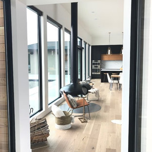 Idee per un grande soggiorno minimalista aperto con pareti bianche, parquet chiaro, camino sospeso, TV a parete e pavimento grigio