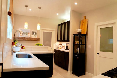 Inspiration for a small modern u-shaped beige floor enclosed kitchen remodel in San Francisco with a peninsula, an undermount sink, glass-front cabinets, black cabinets, quartz countertops, stainless steel appliances and white countertops