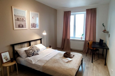 Imagen de dormitorio principal y blanco y madera nórdico de tamaño medio con paredes beige, suelo laminado y suelo beige