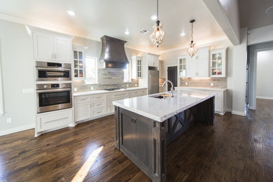 Large transitional l-shaped dark wood floor open concept kitchen photo in Oklahoma City with an undermount sink, shaker cabinets, white cabinets, marble countertops, beige backsplash, stone tile backsplash, stainless steel appliances and an island