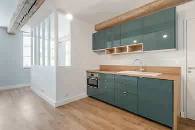 Aménagement d'une cuisine américaine linéaire et encastrable contemporaine avec un évier encastré, un placard à porte plane, des portes de placards vertess, un plan de travail en stratifié et parquet clair.