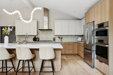 Open concept kitchen - large contemporary l-shaped light wood floor, beige floor and vaulted ceiling open concept kitchen idea in San Francisco with an undermount sink, flat-panel cabinets, light wood cabinets, quartzite countertops, white backsplash, ceramic backsplash, stainless steel appliances, an island and beige countertops