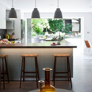 ロンドンのコンテンポラリースタイルのおしゃれなキッチン (フラットパネル扉のキャビネット、サブウェイタイルのキッチンパネル、黒いキッチンパネル、シルバーの調理設備) の写真