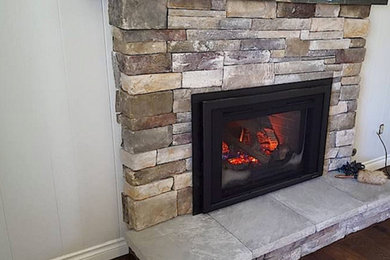 Example of a mid-sized transitional enclosed medium tone wood floor and brown floor living room design in Portland with white walls, a standard fireplace and a stone fireplace