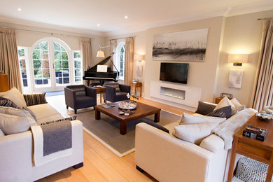 Photo of a large contemporary formal enclosed living room in Surrey with beige walls, light hardwood flooring, a ribbon fireplace, a stone fireplace surround and a wall mounted tv.