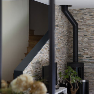 Mittelgroßes, Offenes Modernes Wohnzimmer mit beiger Wandfarbe, hellem Holzboden, Kaminofen, Kaminumrandung aus Metall, beigem Boden und Ziegelwänden in Paris