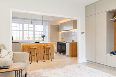 Large contemporary grey and white l-shaped open plan kitchen in Hertfordshire with a submerged sink, flat-panel cabinets, grey cabinets, engineered stone countertops, white splashback, engineered quartz splashback, black appliances, porcelain flooring, an island, beige floors, white worktops and a coffered ceiling.
